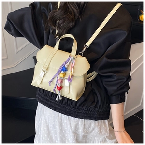 Close-up of cream PU leather backpack featuring a colorful chain and silver buckle detail