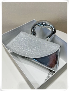 Macro detail of sparkly silver rhinestone mini handbag with chic curved metal handle