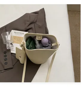 Macro detail of cream bucket bag showing spacious interior with litchi grain texture