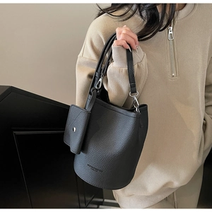 Detail of black lychee texture bucket bag with silver hardware and small side pouch