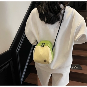 Rear view of model carrying a green and yellow crossbody bag with woven shoulder strap