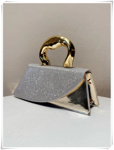 Detailed view of silver sequin flap and circular gold handle on this chic handbag
