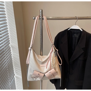 Détail d'un sac cabas beige avec garniture en cuir rose et chaîne en métal argenté élégante