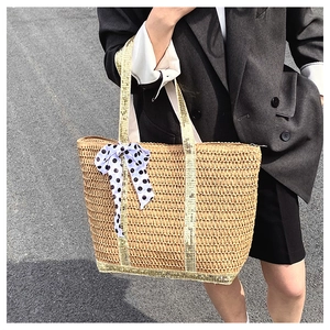 Détail d'un sac cabas en paille orné d'un nœud en ruban à pois noirs et blancs
