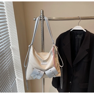 Détail du sac hobo blanc cassé avec chaînes argentées et breloque tissée rose