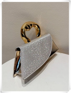 Close-up of sparkling silver rhinestone evening bag with a chunky gold metallic handle