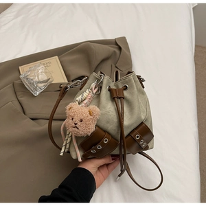 Detailansicht der khakifarbenen Canvas-Beuteltasche mit Lederbesatz und Bären-Anhänger