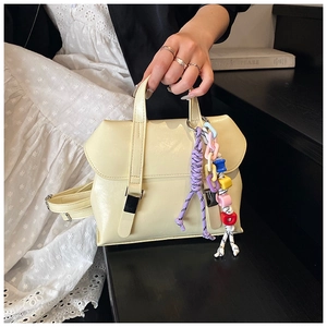 Detail of cream leather bucket bag featuring a colorful charm and silver buckle