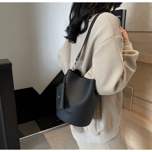 Detail of black lychee grain leather bucket bag with debossed lettering and side pouch