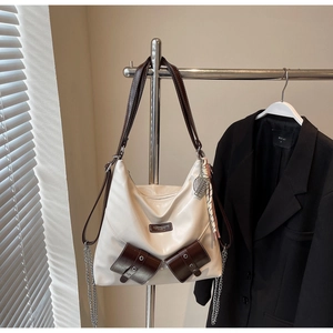 Détail d'un sac cabas blanc cassé avec deux poches brunes et une bandoulière chic
