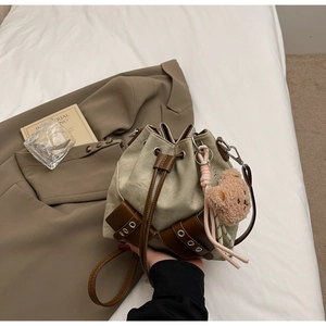 Detail der Canvas-Beuteltasche mit braunem Lederbesatz, Kordelzug und Bärenanhänger