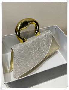 Macro view of silver rhinestones and irregular golden metal handle on the evening bag