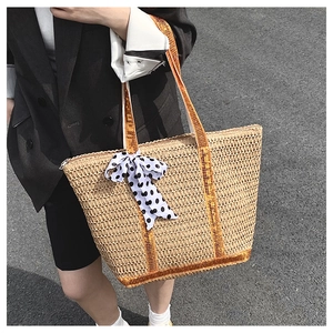 Détail du sac cabas en paille avec rubans orange et breloque noeud à pois pour l'été