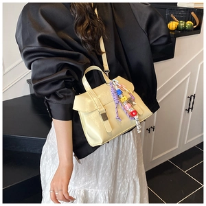 Detail of cream PU leather bucket bag featuring a colorful beaded charm and flap closure