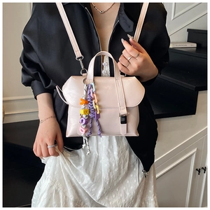 Detail of light beige bucket bag with colorful letter charm and stylish leather texture