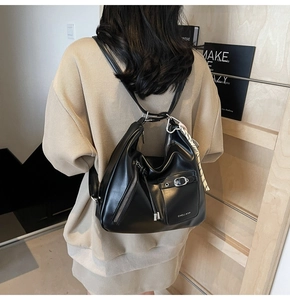 Detailed view of a black faux leather backpack featuring a silk scarf on the handle