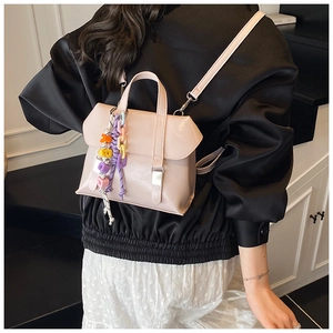 Detail of light pink mini backpack with colorful bead charms and faux leather texture