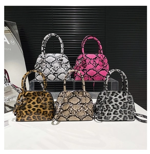 Close-up of five shell-shaped handbags in snake and leopard patterns with silver zippers