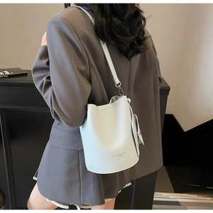 Detail of light blue lychee pattern leather bucket bag worn with a gray suit