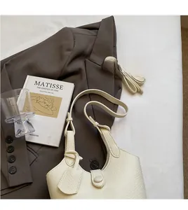 Detail of cream lychee texture leather bucket bag with adjustable shoulder strap and tag