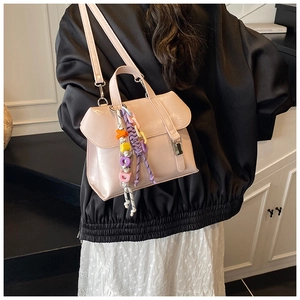 Close-up of light pink leather crossbody bag with decorative alphabet charms on a model
