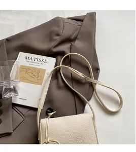 Détail du sac seau crème à texture litchi sur un blazer marron pour le printemps