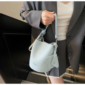 Detail of light blue bucket bag with pebble leather texture and side coin purse accessory