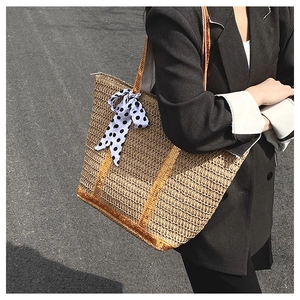 Detail of straw tote bag featuring golden trim and a black and white polka dot scarf