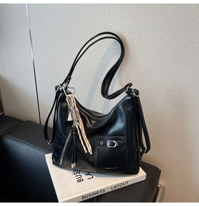 Detail of black hobo bag showing silver metal zippers and buckle pockets on leather