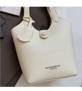 Close-up of litchi grain leather texture and brand logo on cream bucket handbag