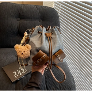 Nahaufnahme der hellblauen Denim-Beuteltasche mit braunem Leder und Plüschbär-Anhänger