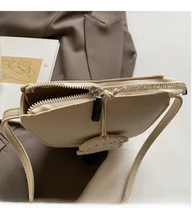 Gros plan du sac seau en cuir beige montrant la fermeture éclair et l'intérieur