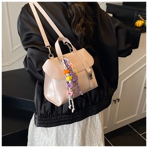 Close-up of a light pink leather crossbody bag with colorful letter charm decorations