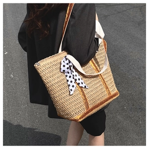 Detail of a woven straw tote bag with orange sequin stripes and polka dot scarf detail