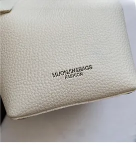 Detail of white lychee grain leather handbag with Muonjin & Bags embossed logo