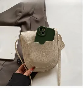 Détail d'un sac à bandoulière en cuir beige grainé avec une poche avant pour téléphone