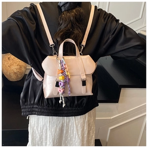 Detail of a light pink mini backpack with colorful letter bead charm and metal hardware
