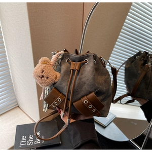 Detail der Vintage-Denim-Beuteltasche mit Lederzugband und Plüschbär-Anhänger