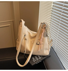 Detail view of cream soft leather tote bag with decorative zipper and tennis racket charm