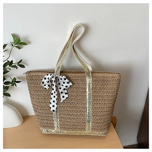 Détail du sac en paille avec rubans à paillettes dorées et nœud à pois élégant