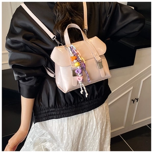 Detail of pink glossy backpack featuring silver buckle and colorful letter charm accessories