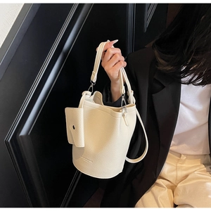 Detail of cream white bucket bag with pebble leather texture and small charm bag