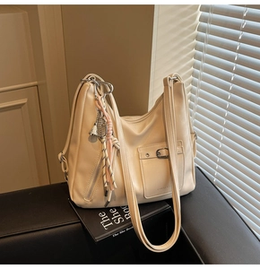 Detail of cream leather tote bag featuring silver hardware and a decorative charm