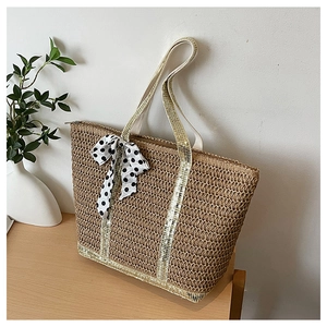 Détail d'un sac cabas en paille avec paillettes dorées et foulard en soie à pois noirs