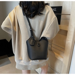 Detail of black pebbled leather bucket bag with top handle and minimalist branding