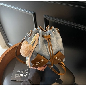 Detail der Jeans-Beuteltasche mit braunem Lederbesatz und süßem Bären-Anhänger