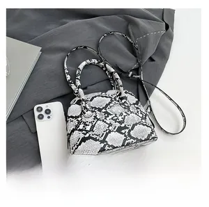 Detailansicht der Schlangenleder-Muscheltasche mit Riemen und Handy als Größenvergleich