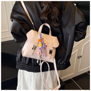 Detail of pink glossy shoulder bag with colorful beaded charm and silver buckle