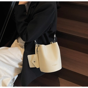 Detail of off-white lychee textured bucket bag with silver hardware and small pouch