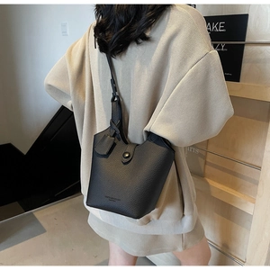 Close-up of a black lychee texture bucket bag with adjustable strap and casual styling